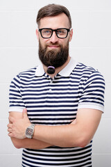 Funny portrait of young man wearing glasses with hair rubber band on his beard