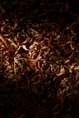 Cut dried tobacco leaves close up background lit bright in the middle