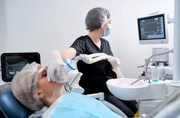 Doctor making anesthesia while female patient lying in dentist chair