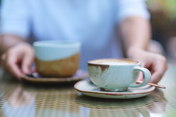 Closeup image of a woman holding and serving two cups of hot coffee