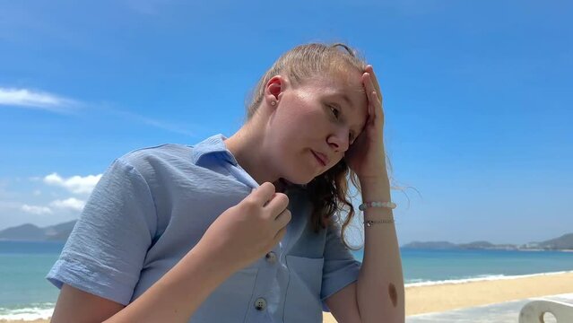 Young woman feeling bad, suffering from sunstroke at sea, beach at summer