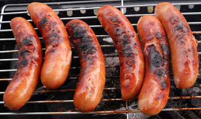 Top view of grilled sausages on charcoal grill.