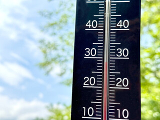 27℃をさす縦型温度計_青空と緑背景
