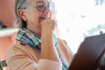Smiling senior woman wearing eyeglasses relaxing at cafe table reading menu, senior lady let her choose, free time concept
