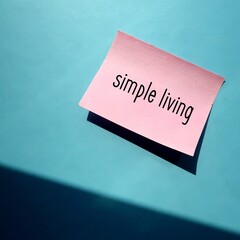 Pink note stick on blue wall with text SIMPLE LIVING ,  practices that promote simplicity in...