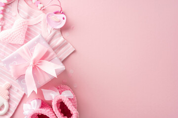 A pink-themed baby shower gift set, including clothes, knitted heart, pacifier, rattle, and a gift box with a ribbon