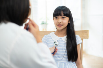 Obraz premium doctor in a white coat conducting a health check on a girl, father by her side.
