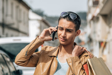 young man with shopping bags on the street and talking on the phone