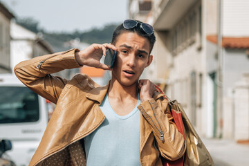 young man with shopping bags on the street and talking on the phone