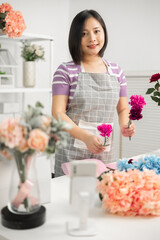 A couple of Asian entrepreneurs using their smartphones to sell flowers online.