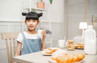 Asian family enjoying a nutritious breakfast at home, with their daughter holding a glass of milk.