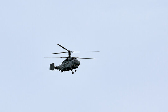 Russian military helicopter armed with missiles flies in blue sky, airborne mission of gunship with targeting system performs an aerial maneuvers for military operation, russian aviation