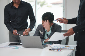 Tired Asian young businessman. Stressed. The man at work has a headache from overwork. Calculating...