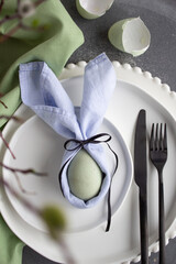 light blue and green easter table setting with white plates, black decorations