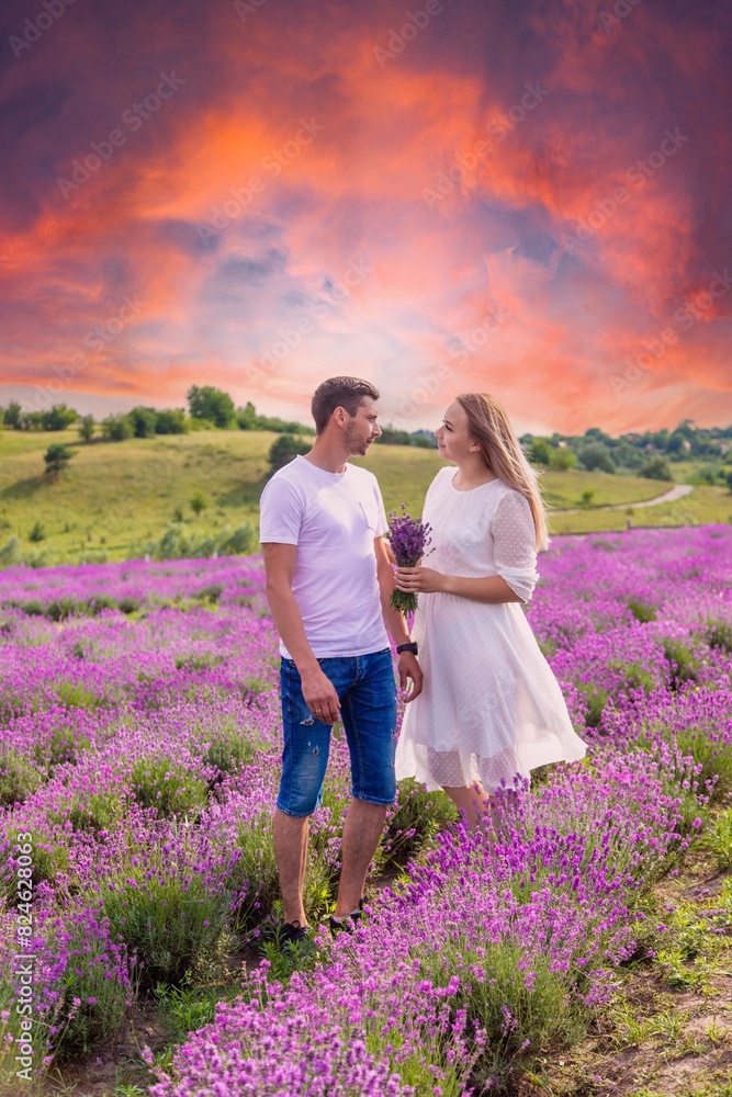 Wall mural Beautiful happy couple in lavender field having fun on flower meadow, summer nature, love concept.