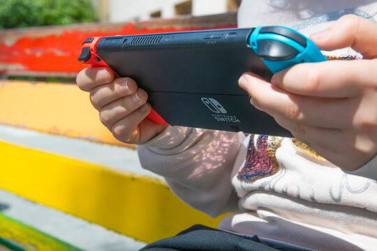 Teenager holding a Nintendo Switch Oled. Outdoor shot. Empty copy space for Editor's text.
