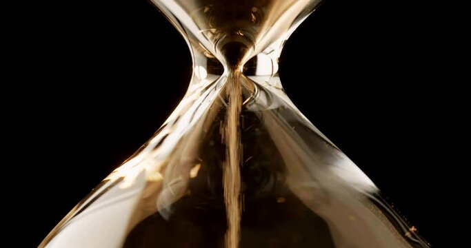 Closeup of sand timer clock with sand flowing from through hourglass on white background.
