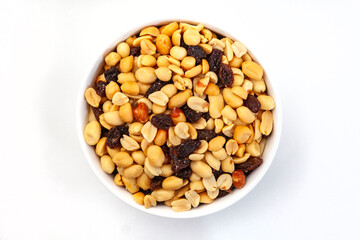 Flat lay, top view of Peanut and raisin mix in round white bowl, isolated on white.