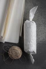 chocolate sausage with cookies and pistachios on a gray background, wrapped in white paper
