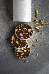 chocolate sausage with cookies and pistachios on a gray background, wrapped in white paper