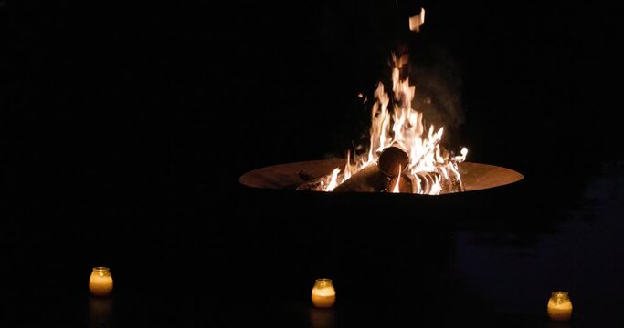 At night, a bonfire surrounded by candles can create a cozy and tranquil atmosphere for a peaceful evening outdoors