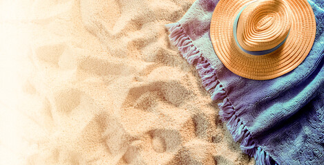 Top view of brown straw hat placed blue blanket on sand beach background on sunny day, with copy space. Summer vacation, holiday travel banner concept.