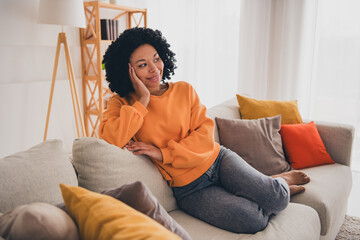 Photo portrait of lovely young lady sit sofa look empty space dressed casual orange clothes cozy...