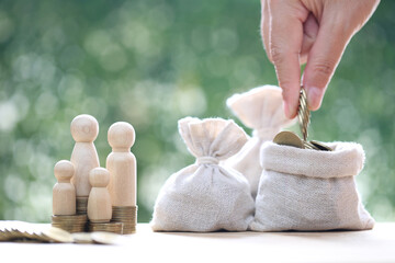 Model family with money bag and stack of coins money on natural green background,Save money for prepare in future and family finance concept
