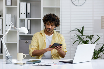 Young professional working at desk with laptop and calculator in modern office