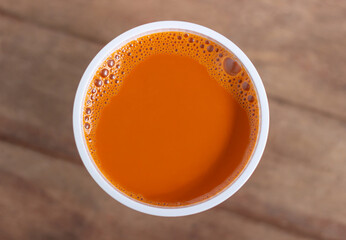 Hot milk tea in a white cup on wooden table background