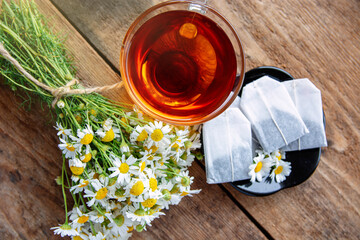 tea bags of chamomile tea and a cup of herbal tea, bouquet of fresh daisy flowers. doctor treatment...