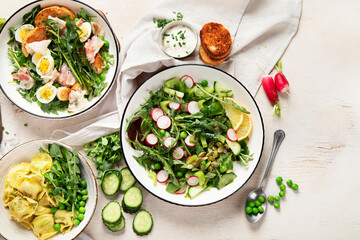 Spring fresh food with green leaf. Salads with strawberries, bacon and ravioli on light wooden background