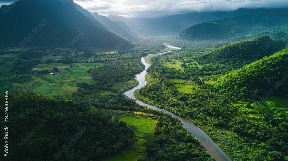 Poster aerial view of a winding river flowing through a lush green valley surrounded by mountains under a c