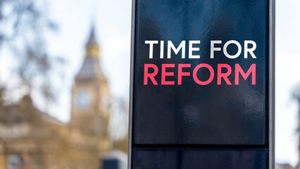 Time For Reform written on a sign with Elizabeth Tower and Big Ben in the background