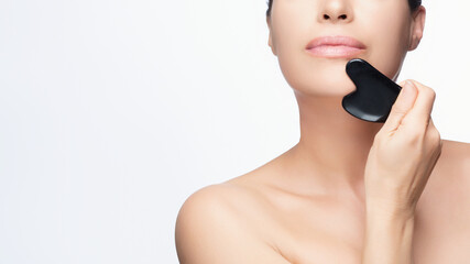 Woman Using Gua Sha Stone for Facial Skincare Routine. Cropped portrait on white background with...