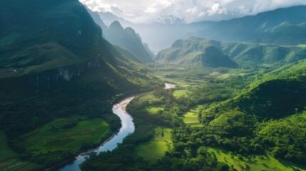 A breathtaking aerial view of lush green valleys, winding river, and towering mountains under a partly cloudy sky. Nature at its finest.