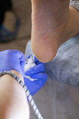 Young woman getting Pedicure with milling cutter in beauty salon, closeup