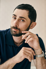 A man in a pensive pose, with one hand placed on his chin, showcasing his thoughtful and...