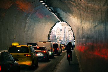 Bicyclist riding along line of cars in the tunnel