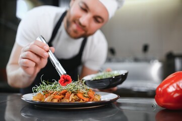 Closeup of a concentrated male chef garnishing food in the kitchen
