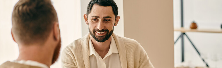 Fototapeta premium Two men, a happy gay couple, gaze at each others eyes in their modern apartment, showing affection.