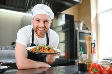 Portrait of handsome positive chef cook at the restaurant kitchen
