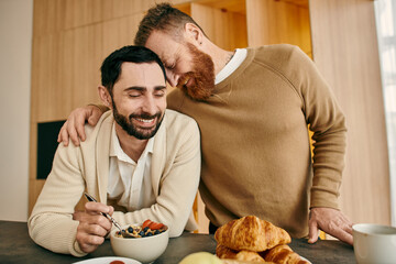 Two men are joyfully sharing breakfast in a stylish kitchen, creating cherished memories together.