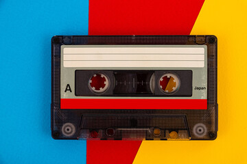 Retro audio cassette tape from the 80s on a color background.