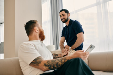 Happy gay couple in casual clothes chatting on a modern couch in their living room, embodying LGBTQ love and connection.