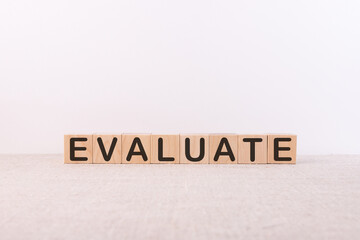 EVALUATE word concept written on wooden cubes on a light background