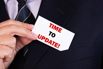 Businessman putting a card with text time to update in the pocket