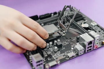 system administrator installing central processor unit into motherboard, assembling PC of different accessories or components, close-up view of hands, computer repair and maintenance concept