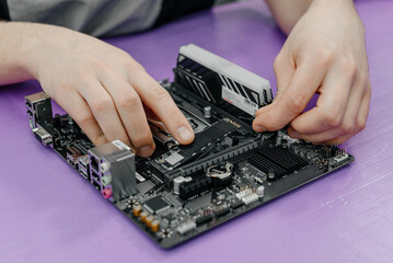 system administrator installing SSD into motherboard, assembling PC of different accessories or components, close-up view of hands, computer repair and maintenance concept
