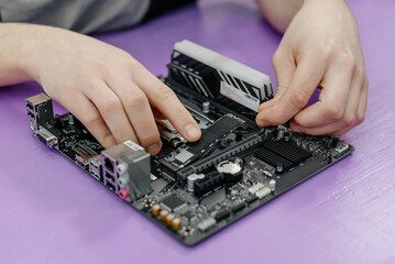 system administrator installing SSD into motherboard, assembling PC of different accessories or components, close-up view of hands, computer repair and maintenance concept